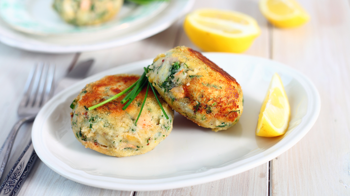Two crispy salmon fishcakes served with a lemon wedge
