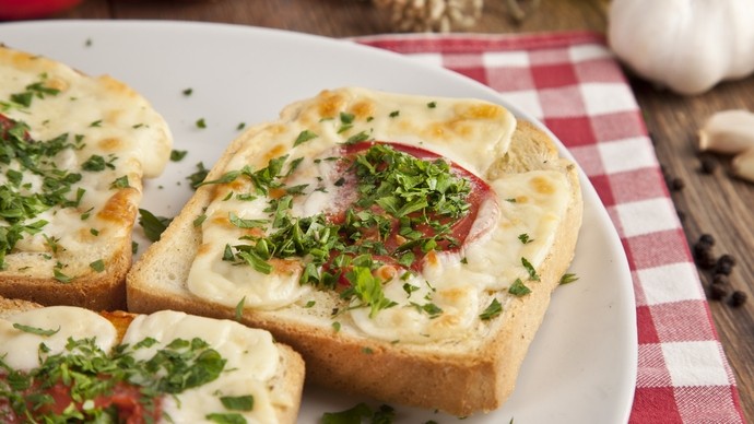 three slices of french toast on a plate topped with cheese, tomato and herb garnish