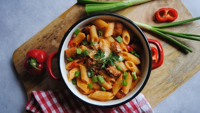 a pasta dish covered in spicy red pepper and crumbled pork sausage meat sauce