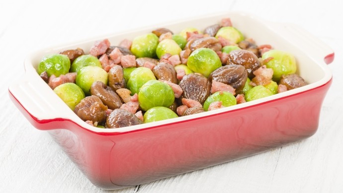 a traybake of brussel sprouts with pancetta pieces and whole chestnuts