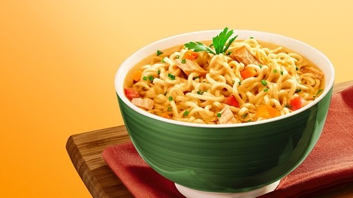 a green bowl containing loads of golden noodles mixed with veggies