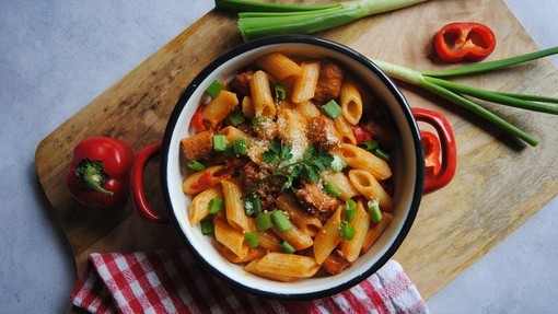 a pasta dish covered in spicy red pepper and crumbled pork sausage meat sauce