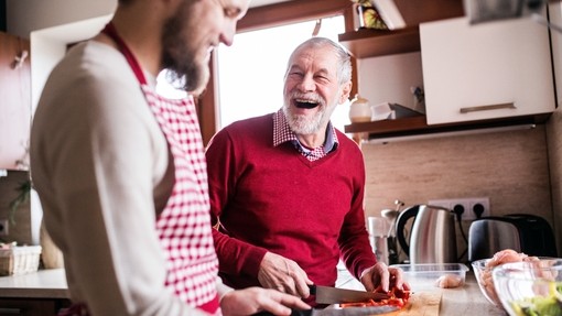 Two white men chopping chillis together in the kitchen: one older and grey, one younger and bearded.