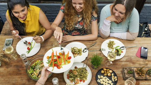 A group of women sharing a meal over a large wooden table