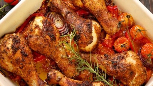 A roasting dish filled with golden roasted chicken and chopped vegetables