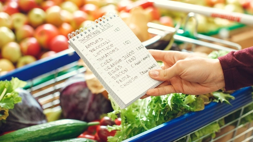 A person holding a paper shopping list in the shop