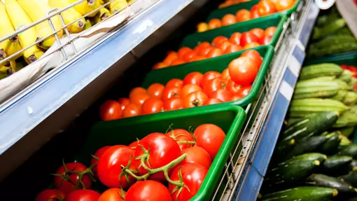 Ffotograff o dybiau o fananas, tomatos a letys yn cael eu harddangos mewn archfarchnad.