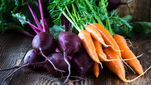 Beetroots and carrots with tops laid out on a table