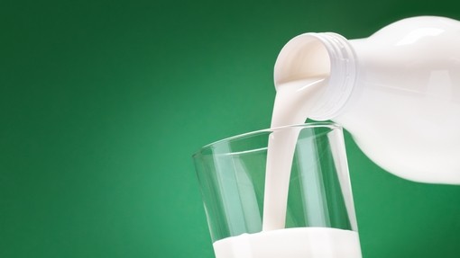 Milk being poured into a glass on a green background