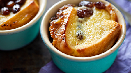 Small ramekins of soft bread and butter pudding topped with berries