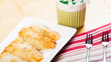 Two flaky cheese filled pasties on a white plate