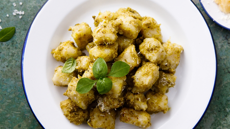 Creamy vegan gnocchi served on a white plate with a green garnish