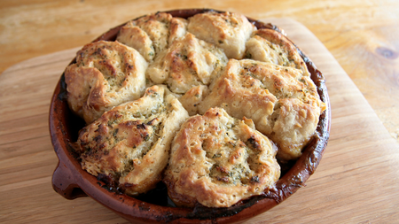 Four baked swirls of savoury bread and butter pudding in a round ceramic dish