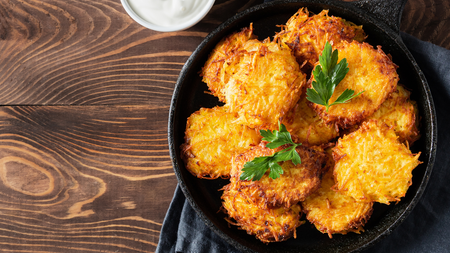 Golden potato hash pieces piled on a plate and topped with garnish