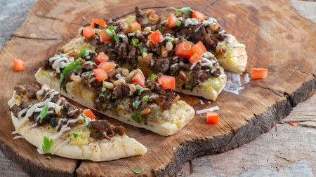 a crispy flatbread topped with lamb mince, chopped tomatoes and cheese