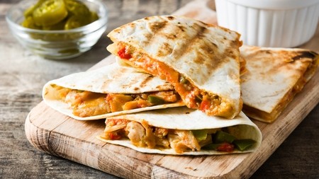 a delicious serving of filled quesadillas containing a rich cheesy sauce and assortment of veggies 