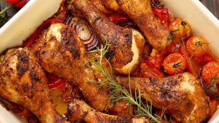 A roasting dish filled with golden braised chicken and chopped vegetables