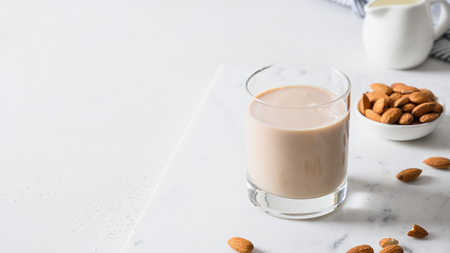 A glass of almond milk next to a handful of whole almonds 