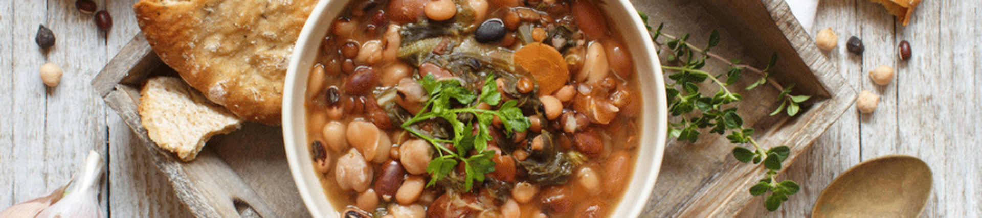 A bowl of mixed lentils and beans with served with two crispy breads
